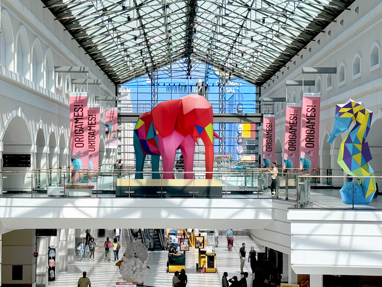 Un atrio del centro commerciale con sculture di elefanti e cavalli colorati in stile origami e striscioni rosa Origames!!!.
