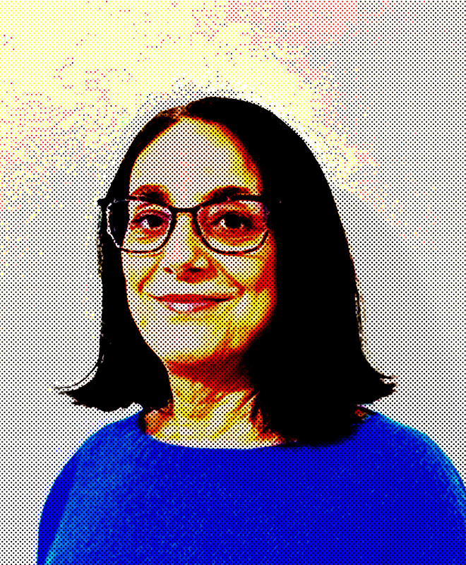 Una donna con capelli scuri lunghi fino alle spalle e occhiali sorride, indossando un top blu su uno sfondo chiaro.