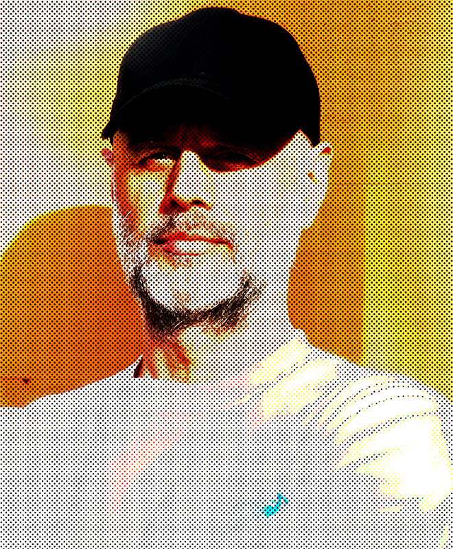 Un uomo barbuto con un berretto nero si trova in piena luce, su uno sfondo giallo-arancio con effetto mezzotono.