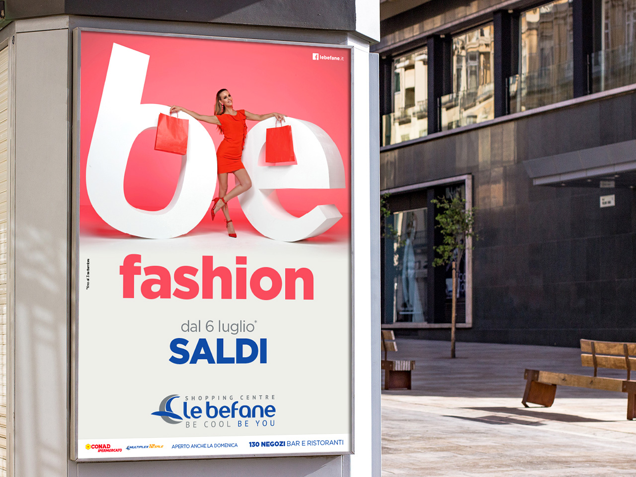 Un manifesto di vendita di moda mostra una donna in rosso con in mano delle borse della spesa, in piedi sulla parola be. Il testo promuove una svendita che inizierà il 6 luglio.