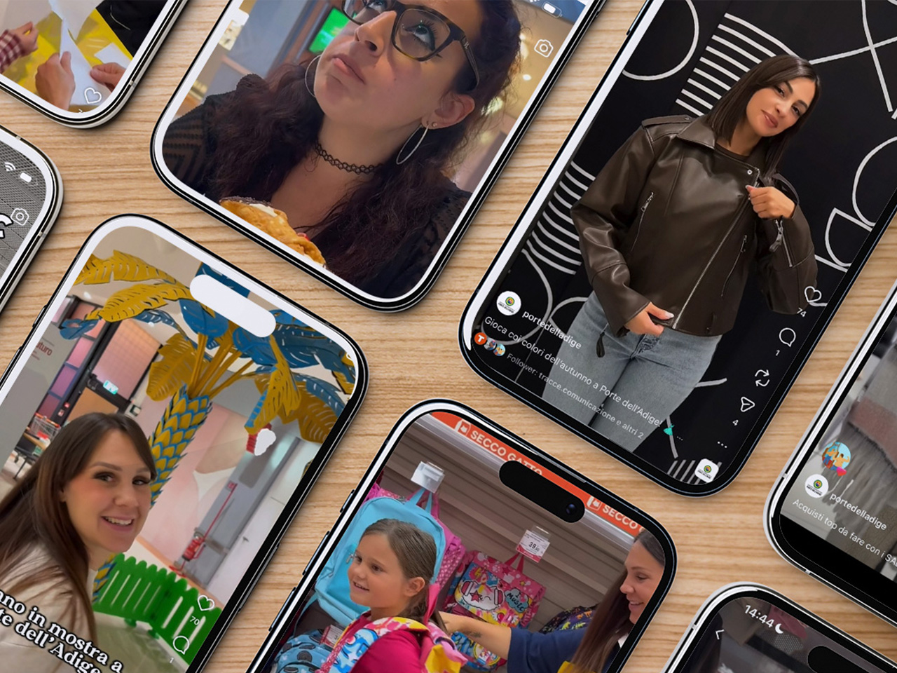 Diversi smartphone su una superficie di legno mostrano giovani donne in posa o che interagiscono in vari video sui social media.