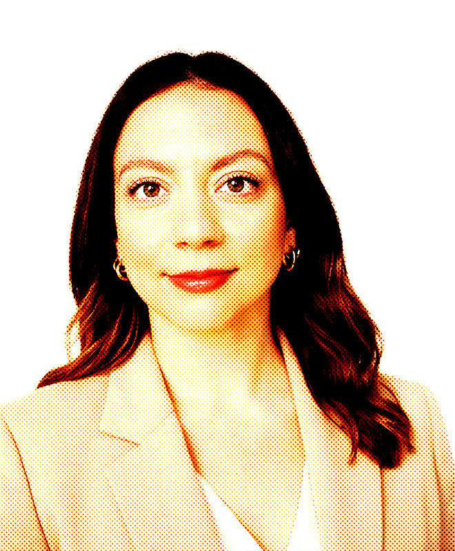 Ritratto di donna con lunghi capelli scuri, che indossa un blazer chiaro e guarda in avanti con espressione neutra.